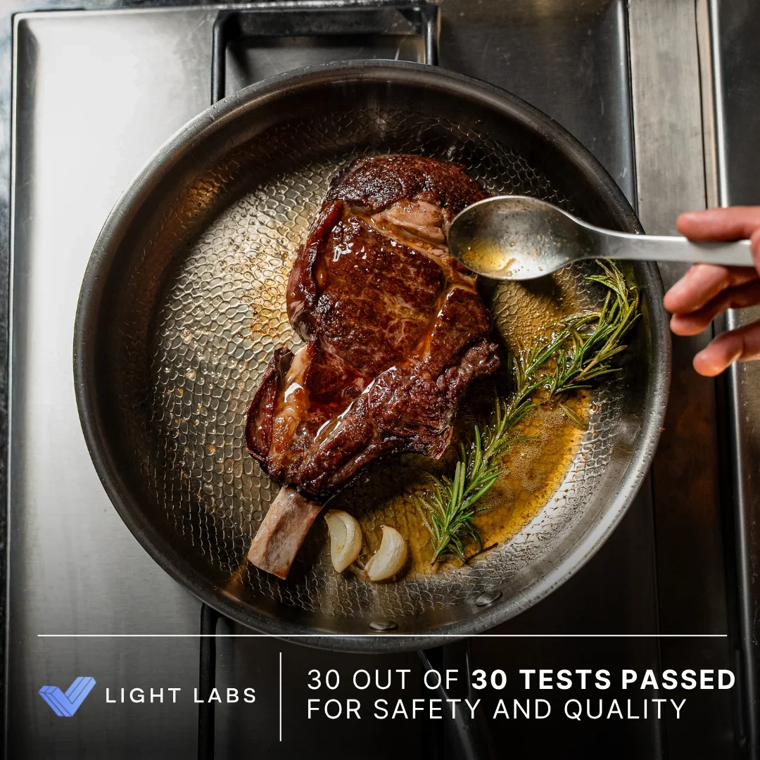 Tomahawk steak searing in Siraat titanium pan with Light Labs certification badge - 30 out of 30 tests passed for safety and quality
